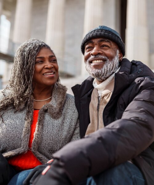 Older couple smiling, sitting on the steps of a monument in D.C.